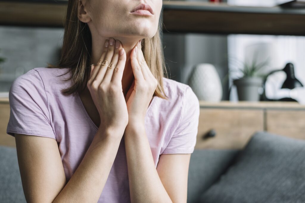 Woman feeling her neck where the thyroid gland is