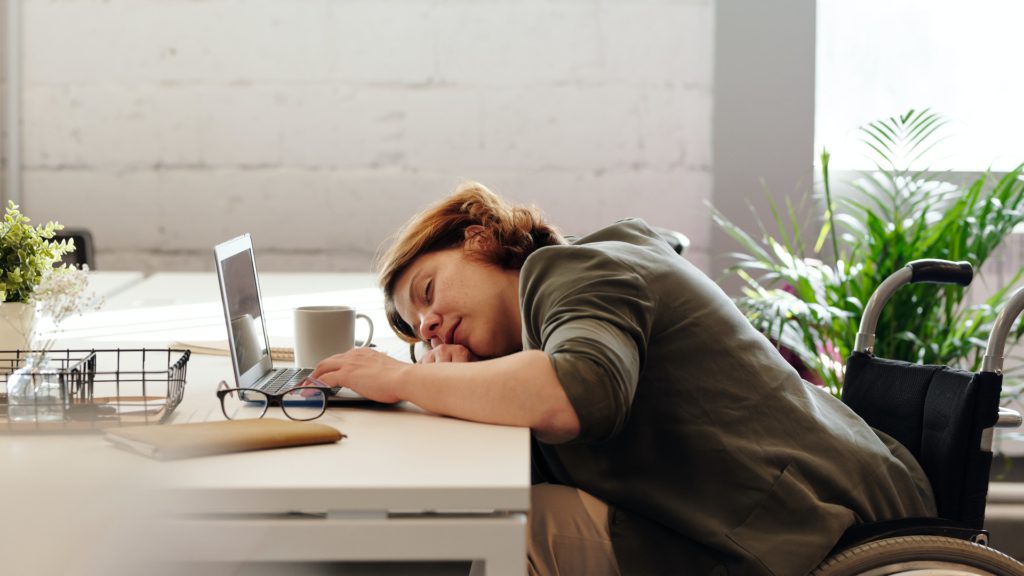 Woman with chronic fatigue syndrome sleeping at her desk