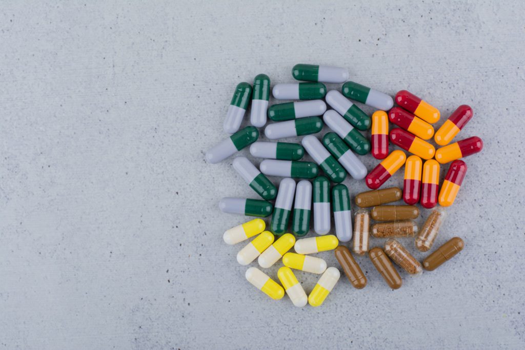 Assorted medical capsules on a marble surface.