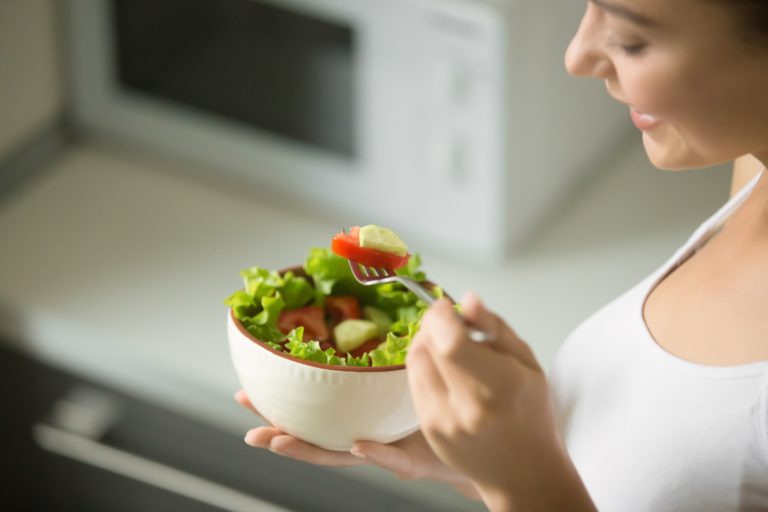 Young woman with a healthy diet eating a bowl of salad