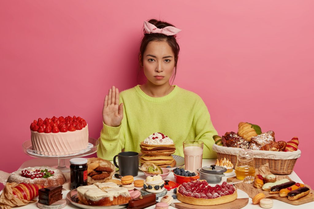 Young woman looking serious with unhealthy food infront of her